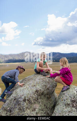 Children exploring rock formations in remote landscape Stock Photo