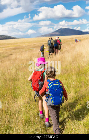 Caucasian children walking in grassy field in remote landscape Stock Photo