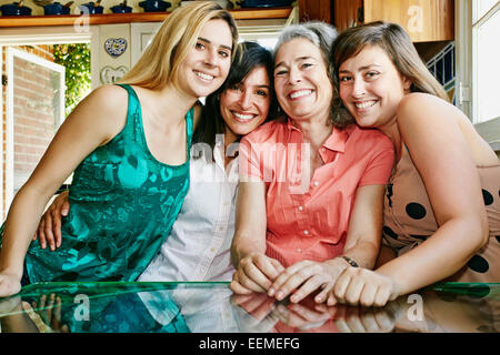 Caucasian mother and daughters hugging in kitchen Stock Photo