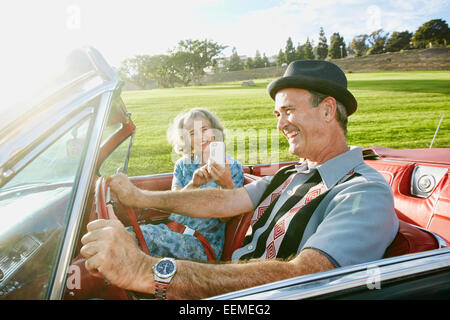 Couple taking cell phone photograph in classic convertible Stock Photo