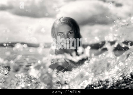Caucasian girl splashing in lake Stock Photo