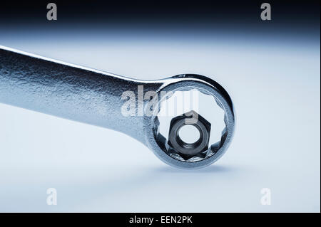 Wrong sized wrench for hex nut mismatch metaphor on graduated background Stock Photo