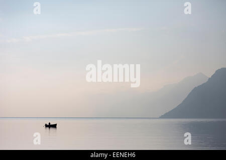 A lone boat on the horizon of the vast of the lake Garda in the northern Italy with light blue morning skies. Stock Photo