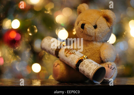 Teddy bear and Christmas cracker with lights in the background UK Stock Photo