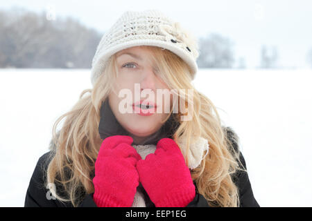 winter woman in snow photo, looking and blows breath at camera outside on cold winter day. Portrait Caucasian female model with  Stock Photo