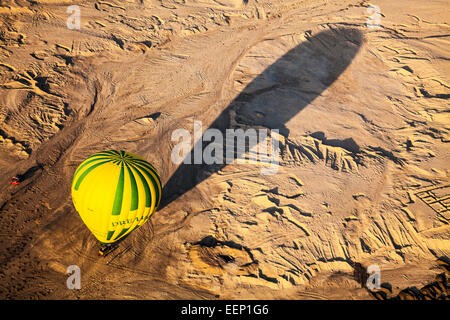 A hot air balloon casts a long shadow as it lands in the desert on the West Bank of the Nile in Egypt. Stock Photo