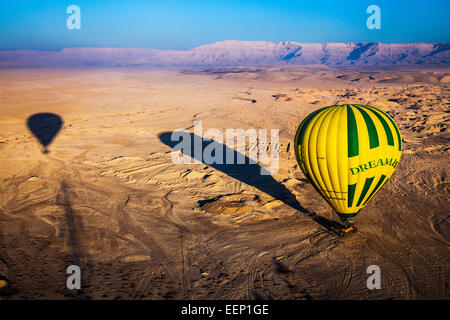 A hot air balloon casts a long shadow as it lands in the desert on the West Bank of the Nile in Egypt. Stock Photo