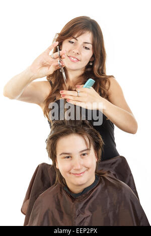 cute young male chubby child kid or boy smiling with long hair at happy female hairdresser cutting his hair while he sitting in  Stock Photo