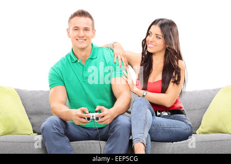 Girl watching her boyfriend play video game seated on a sofa isolated against white background Stock Photo