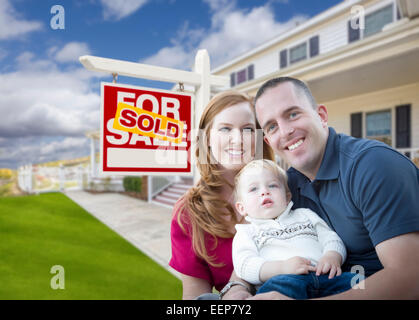 Happy Young Military Family in Front of Sold Real Estate Sign and New House. Stock Photo