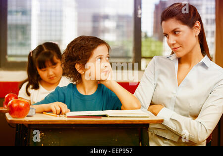 Teacher and schoolboy looking each other in primary classroom. Stock Photo