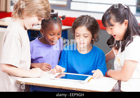 Multi-ethnic classroom playing with tablet. Happy school concept. Stock Photo