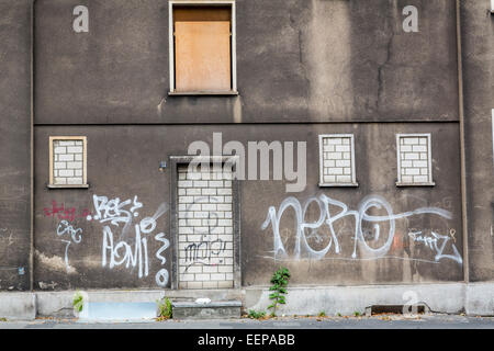 Empty house, run down, doors and windows are bricked and partly covered with wood panels, vacancy Stock Photo