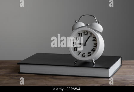 Alarm clock standing on of closed book Stock Photo