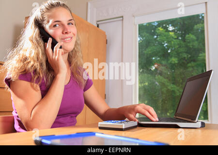 Student with visual impairment talking on her cell phone and using her talking computer Stock Photo