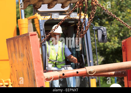 Excavator operator lifting shoring attached to bucket Stock Photo