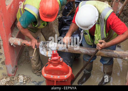 Construction workers adjusting gate valve position on water main Stock Photo