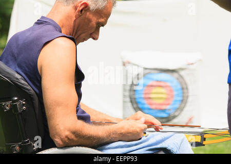 Man with spinal cord injury preparing bow and arrows for target practice Stock Photo