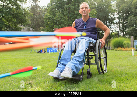 Man with spinal cord injury in wheelchair preparing for archery practice Stock Photo
