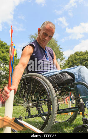 Man with spinal cord injury in wheelchair preparing for archery practice Stock Photo