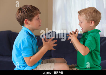 Boys with hearing impairments signing 'football' in American sign language on their couch Stock Photo