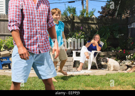 Family with hearing impairments playing football and signing in American sign language in backyard Stock Photo