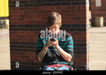 Trendy man with a spinal cord injury in wheelchair taking his text messages Stock Photo