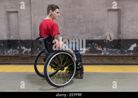 Trendy man with a spinal cord injury in wheelchair waiting for a subway train Stock Photo