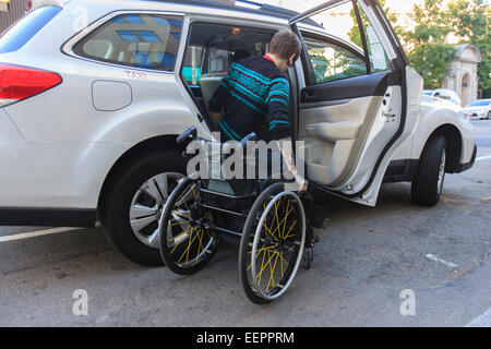 Trendy man with a spinal cord injury in wheelchair getting into a taxi cab Stock Photo