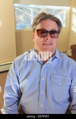 Man with congenital blindness sitting in his living room Stock Photo