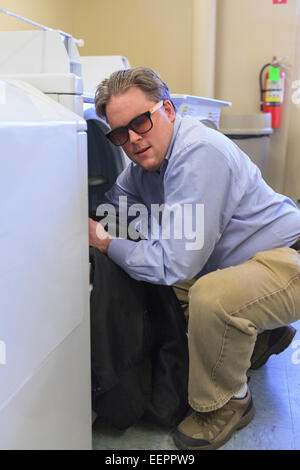 Man with congenital blindness putting his laundry into the washing machine Stock Photo