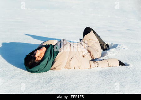 girl lying in the snow on a sunny day Stock Photo