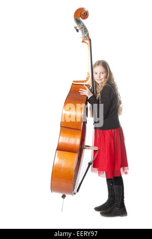 young blond girl in red dress leans against double bass in studio with white background Stock Photo