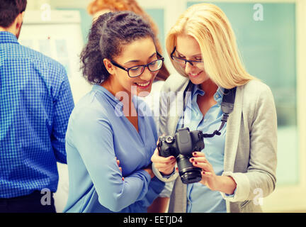 two women looking at digital camera at office Stock Photo