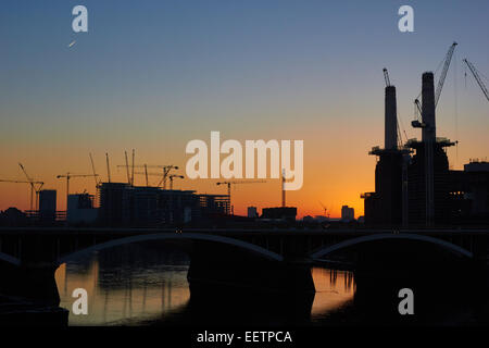 Battersea Power Station chimneys and cranes silhouetted at sunrise London England Europe Stock Photo