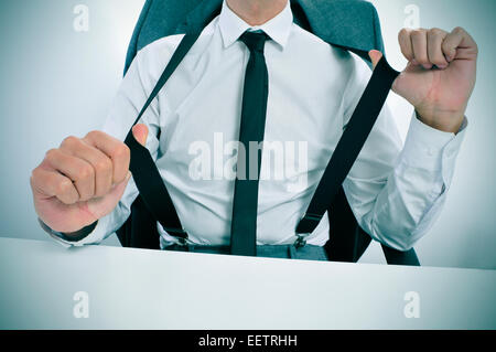 a young businessman in suspenders sitting at his office desk Stock Photo