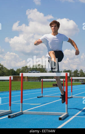 Man jumping hurdles on a track Stock Photo - Alamy