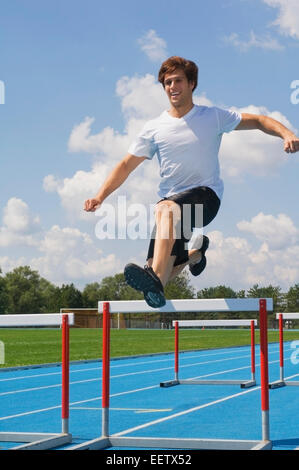 Man jumping hurdles on a track Stock Photo - Alamy