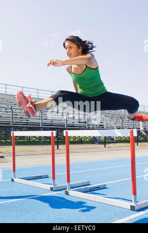 Woman jumping hurdles Stock Photo