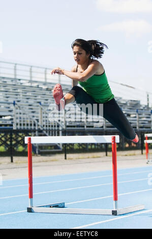 Woman jumping hurdles Stock Photo