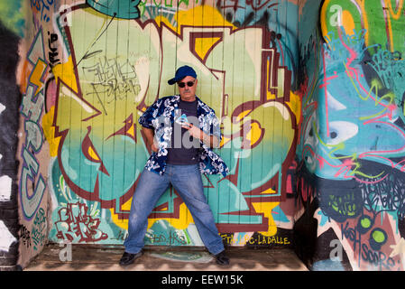Mature male makes a gangster pose in front of a graffiti background Stock Photo