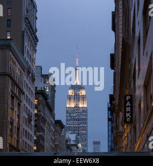 Dusk view of the lit Empire State Building with circling Helicopter. It circles the antenna at the top of the iconic building Stock Photo