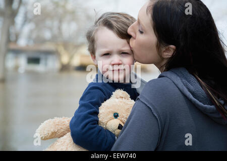 Mother with son standing in flooded town Stock Photo