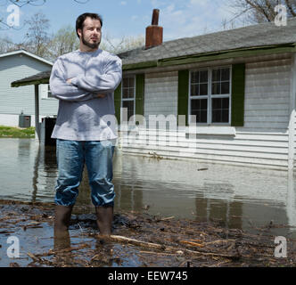 Man standing in front of flooded house Stock Photo