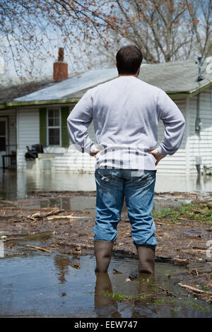 Man standing in front of flooded house Stock Photo