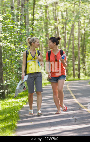 Two girl friends walking on a bike path in the forest Stock Photo