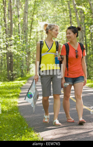 Two girl friends walking on a bike path in the forest with a map Stock Photo