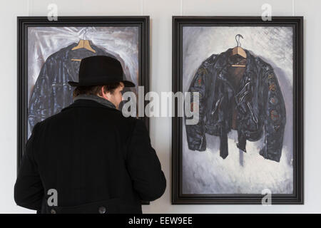 London, UK. 20 January 2015. Pictured: a visitor to the exhibition looks at the paintings 'Joe's Jacket' and 'Rocker', both 2014. The exhibtition 'Wot no Bike' is a series of new paintings by artist, musician and biker Paul Simonon presented at London's ICA. In these oils on canvas, Simonon, the former bass guitar player with the punk band The Clash, depicts his own personal effects that include biker paraphernalia such as jackets, boots, helmets and gloves alongside packs of cigarettes and books. The exhibition at the ICA runs from 21 January to 6 February 2015. Stock Photo