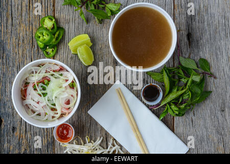 Pho Fast Food To Go on Wood Background with Peppers and Basil Stock Photo