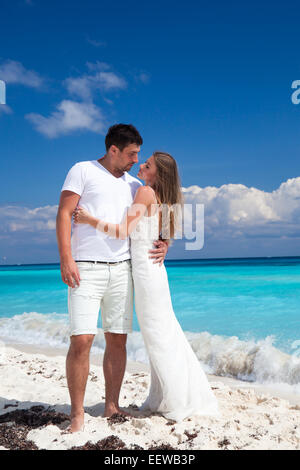 Bride and groom looking to each other and holding hands, romantic vacation at Caribbean beach Stock Photo